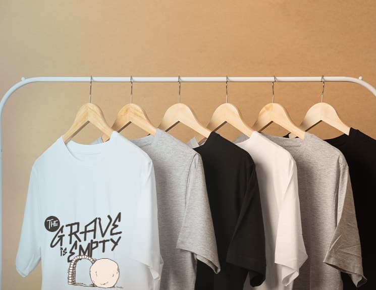 A rail of ADULLAM T-shirts, led by a white “The Grave Is Empty” graphic tee.